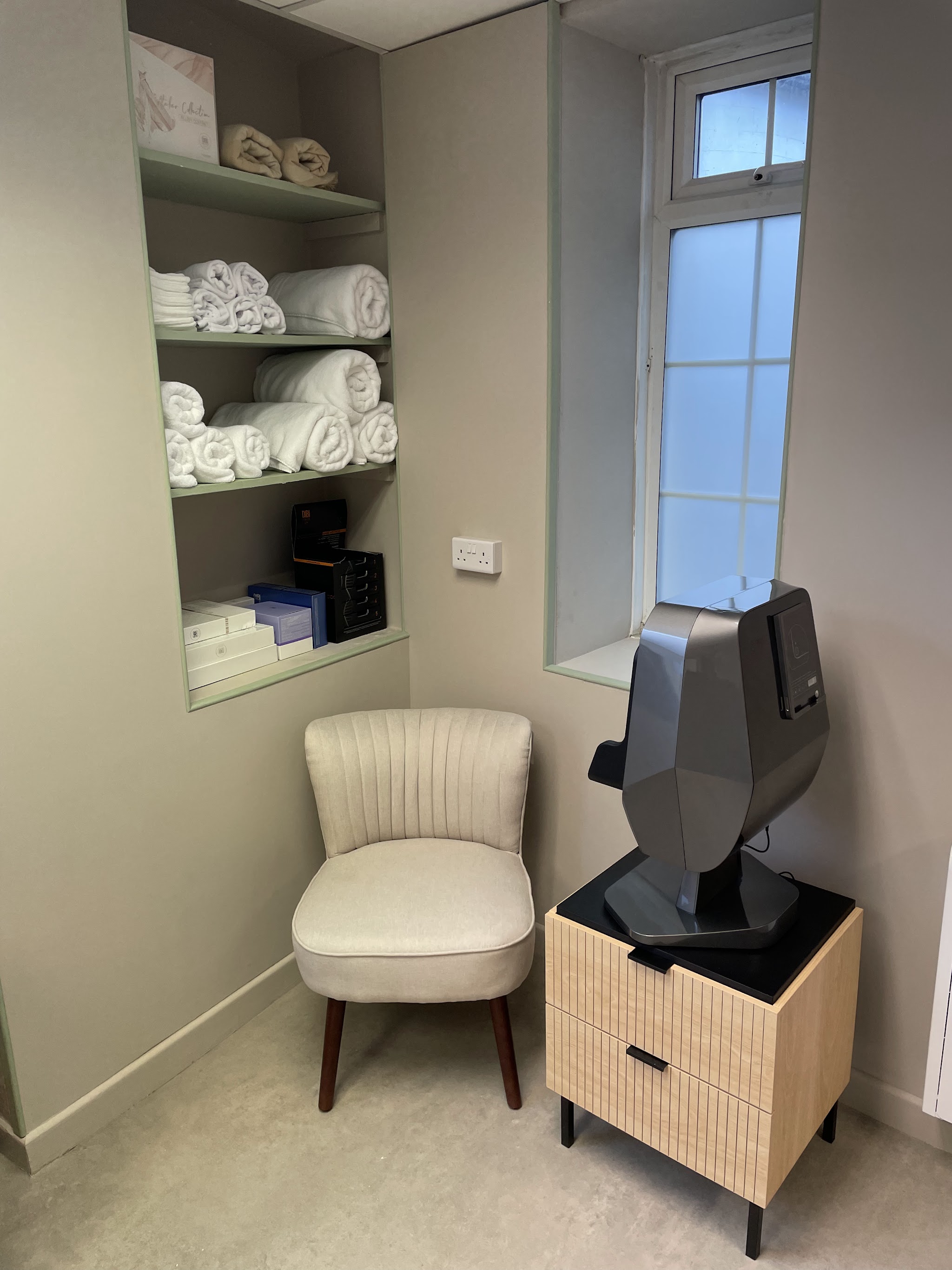 A quiet corner of the treatment room with an armchair, fresh towels and the skin analyser