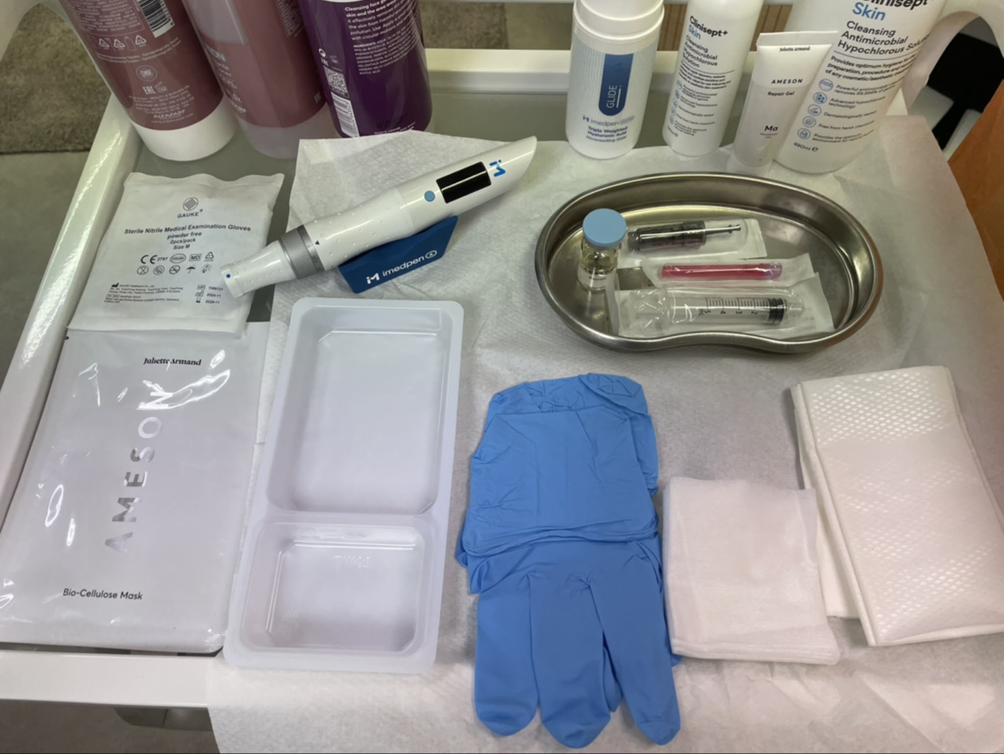 A microneedling set-up: the pen, sterile packs and gloves laid out on the trolley