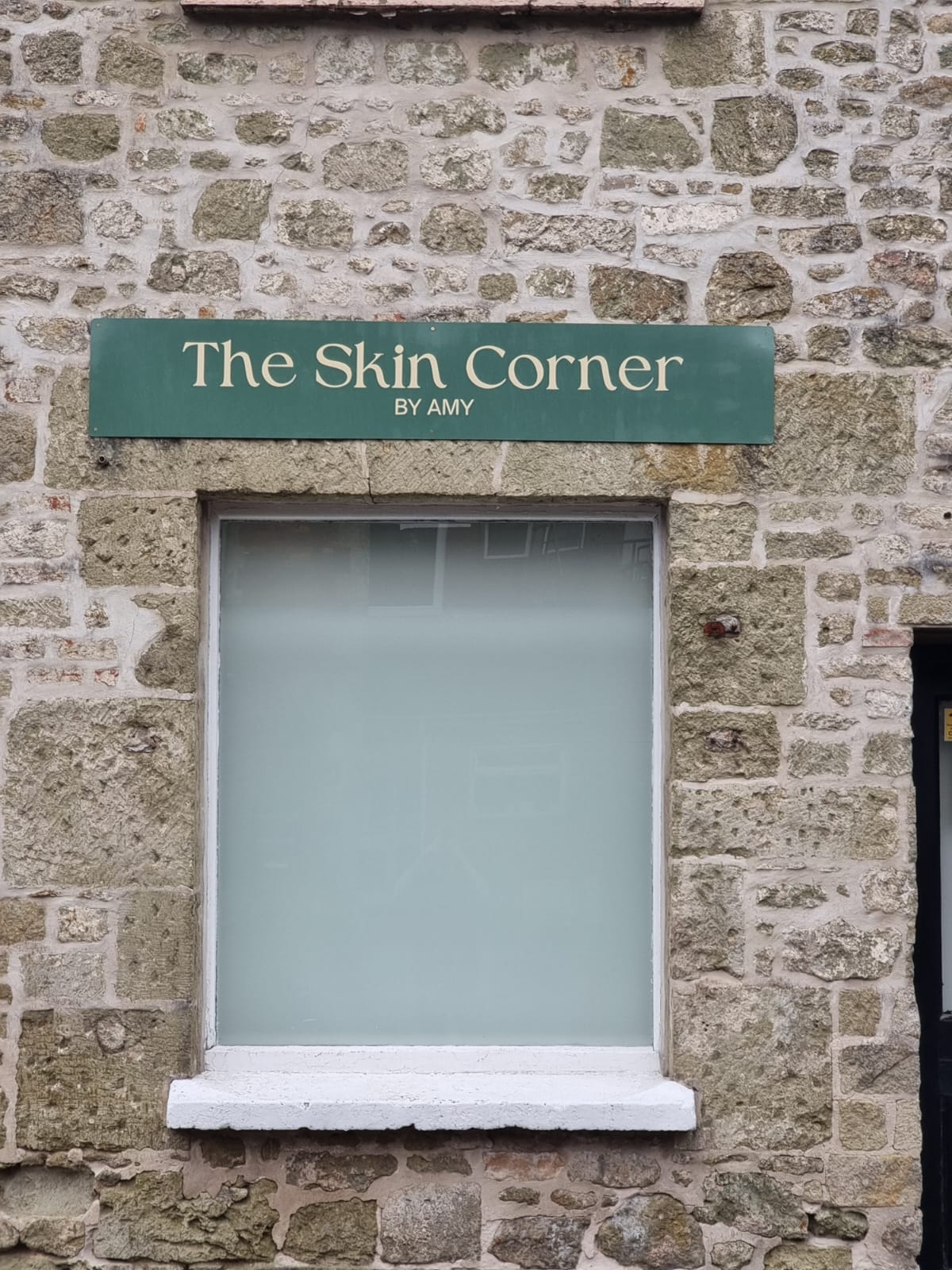 The Skin Corner by Amy sign above the window, on the stone wall at 8 High Street